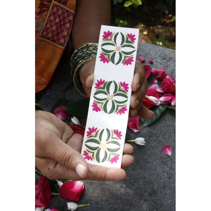 Marcapáginas Botánic con diseño floral en tonos dorado, verde y fucsia, sostenido en las manos